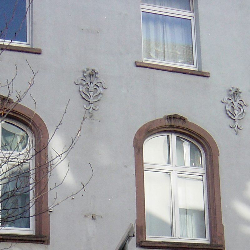 Detail einer Putzfassade mit Stuckornament und Bogenfenster